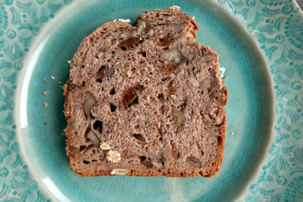 Reference photograph of an apricot and walnut bread slice showing pieces of dried fruit and nuts.